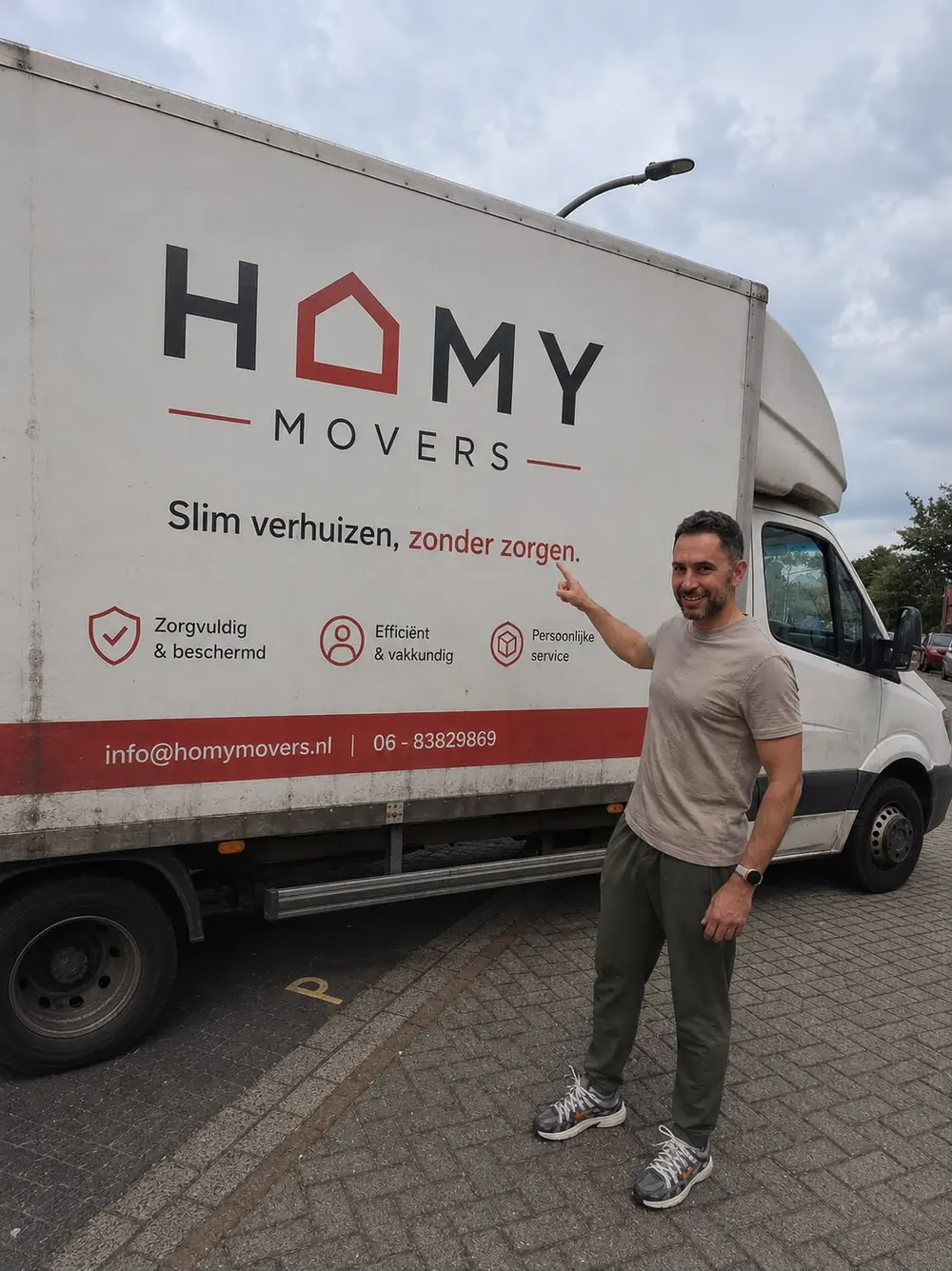Tevreden klant wijst naar de slogan op de HomyMovers verhuiswagen